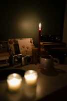 Ambient photo of a dimly lit studio corner with candles and instruments layered in shadows.