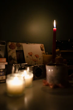 A dimly lit room with scattered old photographs and a flickering candle.