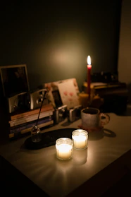 Cozy workspace with soft beige tones and a warm burgundy notebook beside a glowing candle.