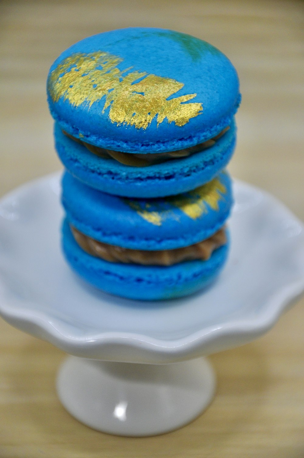 a stack of blue and gold macaroons on a white plate