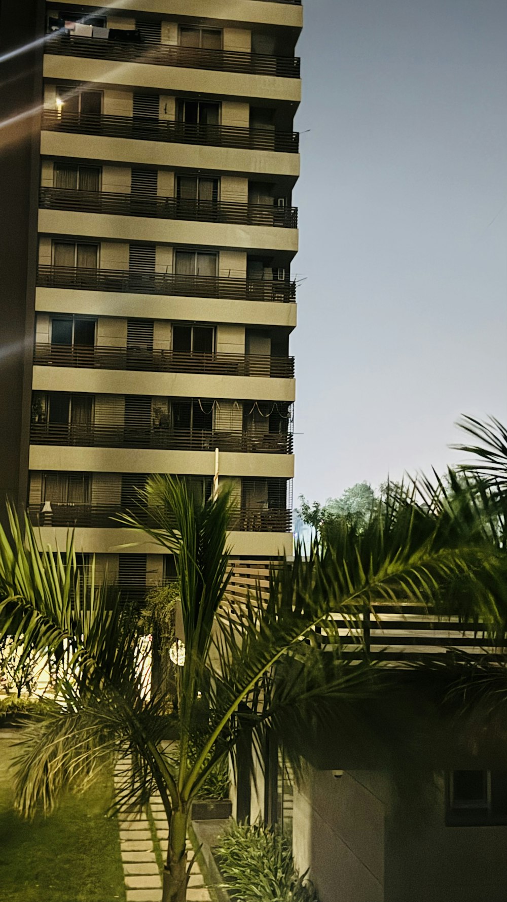 a tall building with balconies next to a palm tree