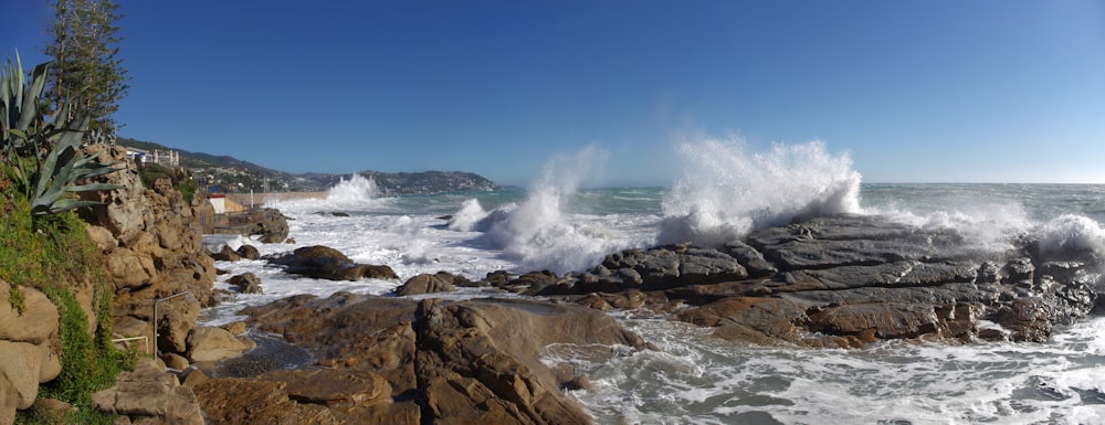 a large wave crashes against a rocky shore