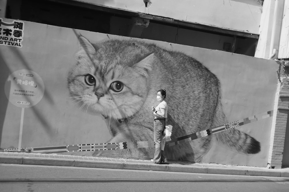 a man standing in front of a large painting of a cat