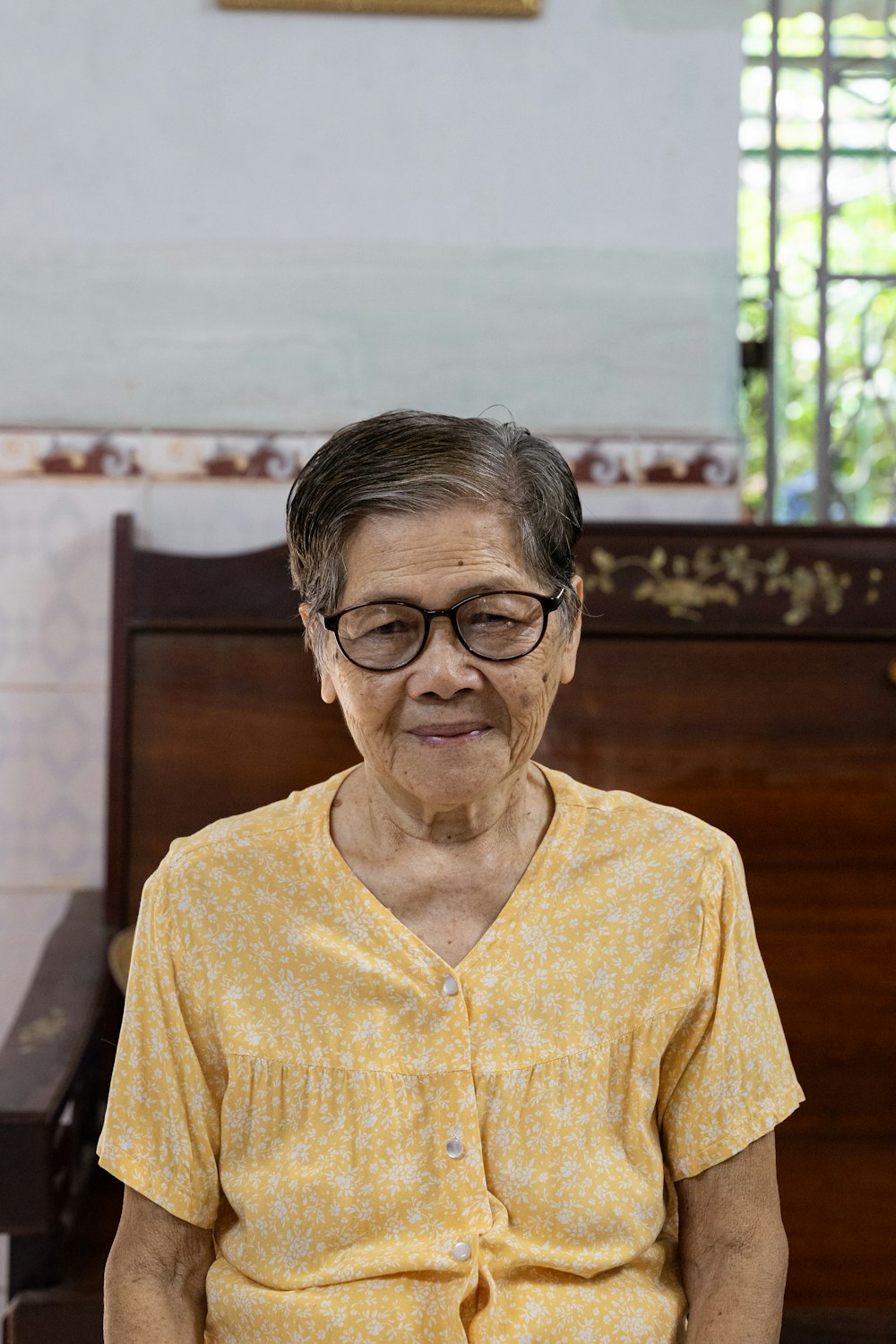 an elderly woman sitting on a bench in a church