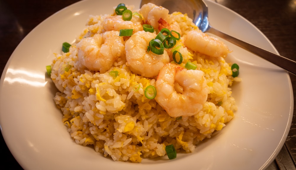 un plato blanco cubierto con arroz y camarones