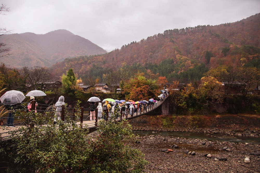 a group of people standing on a bridge with umbrellas