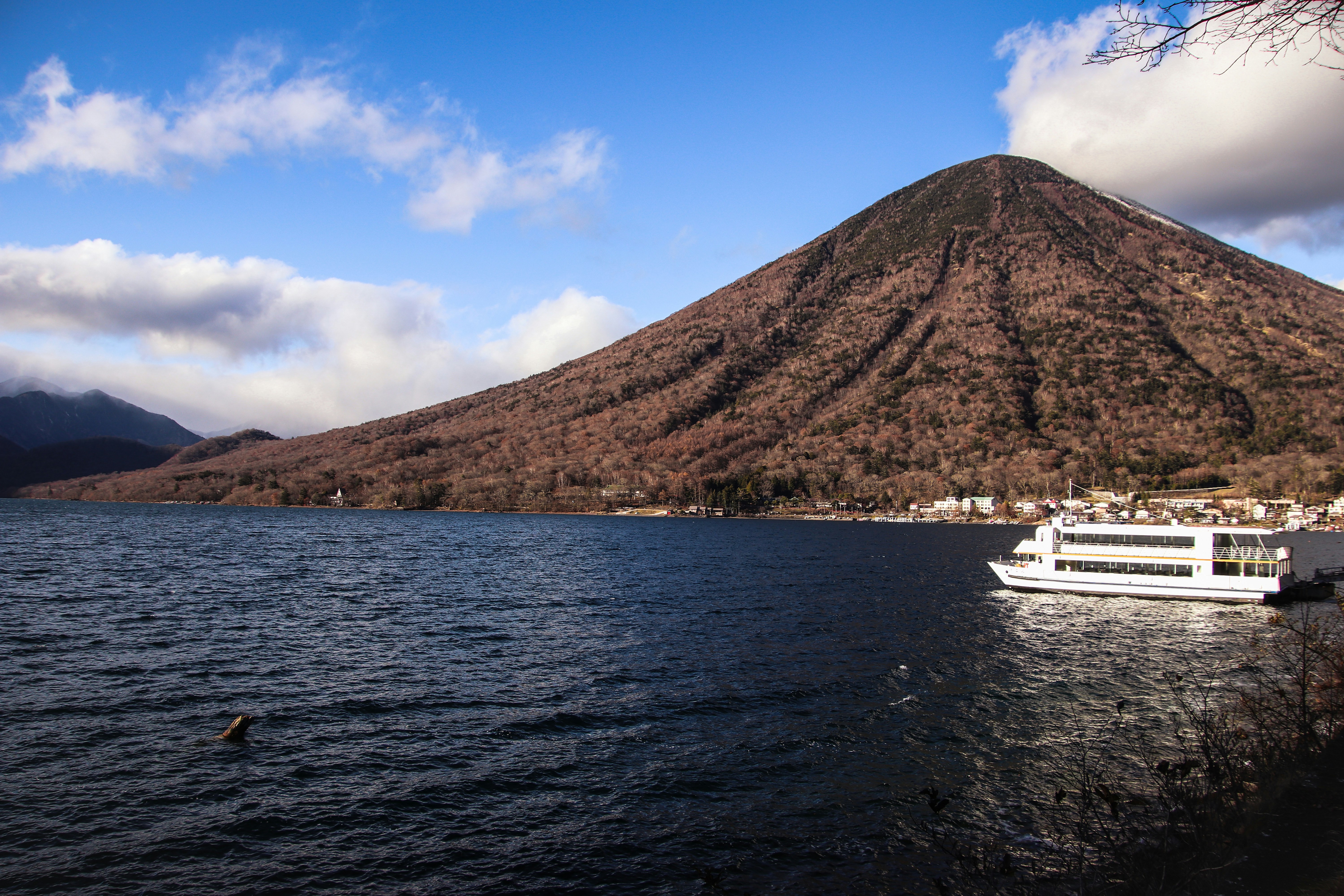 ein großes Boot, das auf einem See neben einem Berg schwimmt