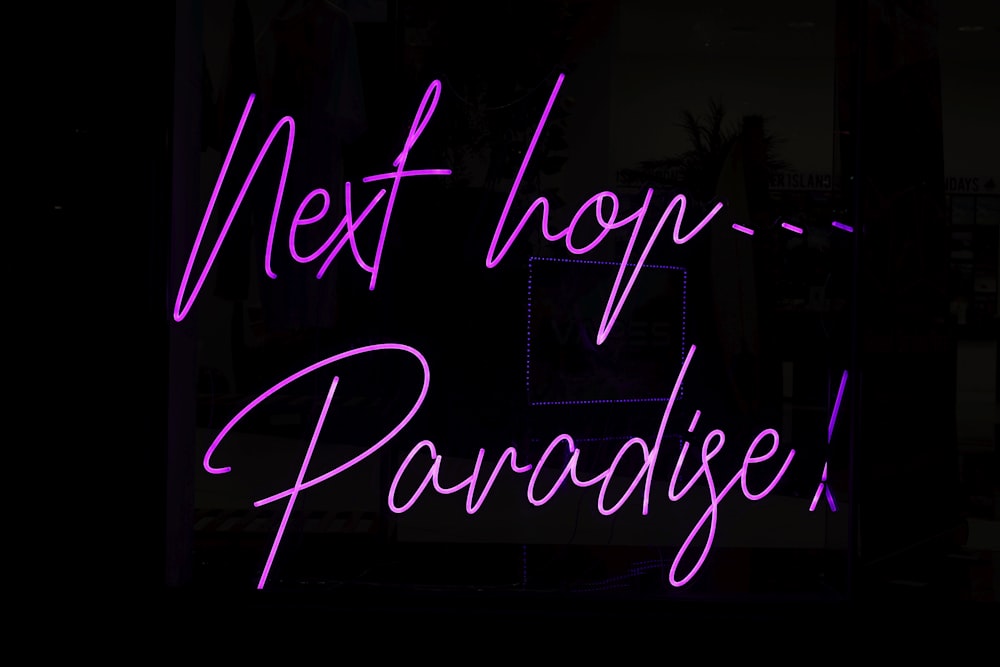 Un'insegna al neon con la scritta Next Hopp - Paradise