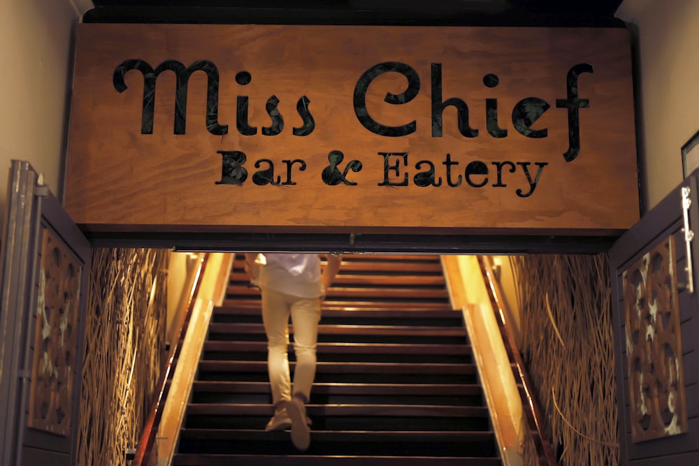 a man walking down a flight of stairs under a sign