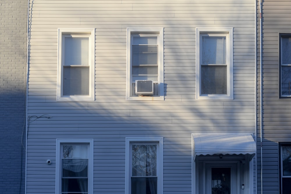 uma casa branca com três janelas e um relógio na frente