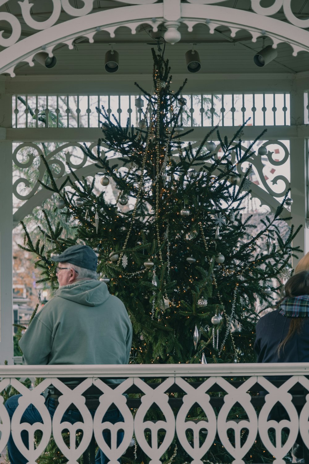 a man and a woman sitting on a bench in front of a christmas tree