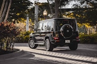 A uniformed driver greeting a corporate client warmly beside a black Mercedes-Benz at the airport pickup zone.