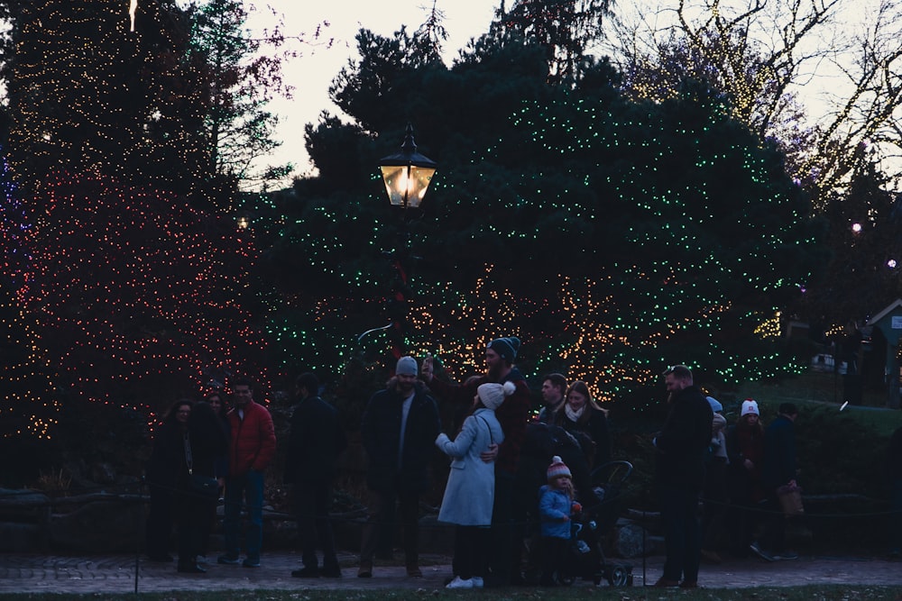 a group of people standing around a christmas tree