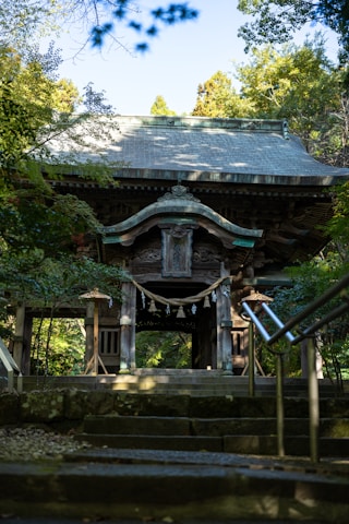 Sunlight filtering through the temple’s intricately carved wooden entrance, inviting visitors inside.