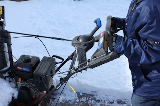 A clean, well-maintained snowblower ready for winter service on a snowy driveway.