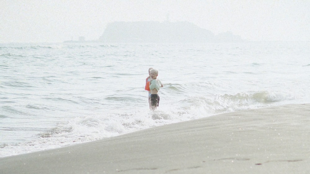 a little boy standing in the water at the beach