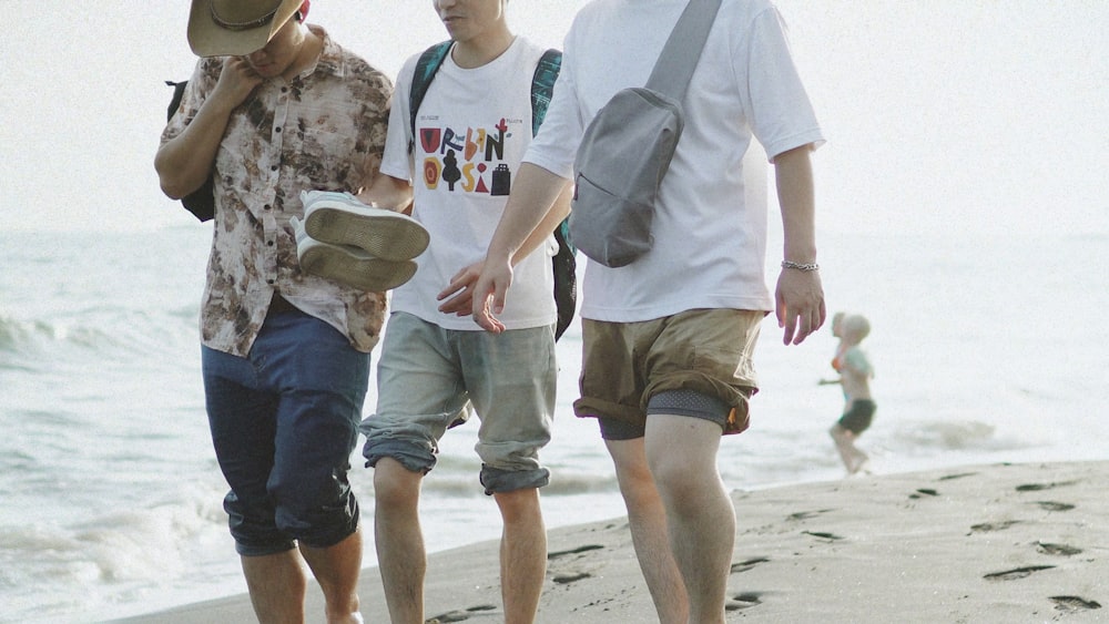 a group of men walking along a beach next to the ocean