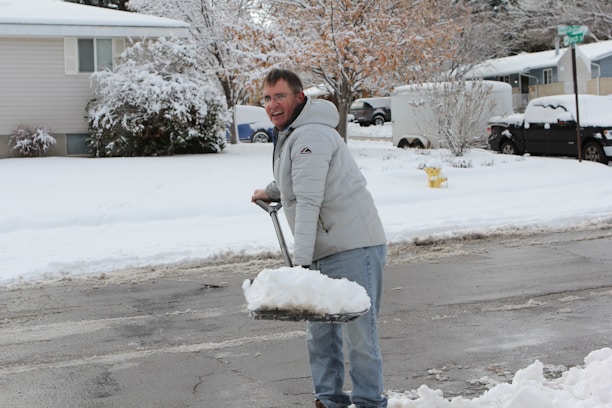 Close-up of Jason Frost smiling while working with a snow shovel in a residential yard.