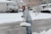Smiling woman standing next to a cleared driveway with a snow shovel in hand.