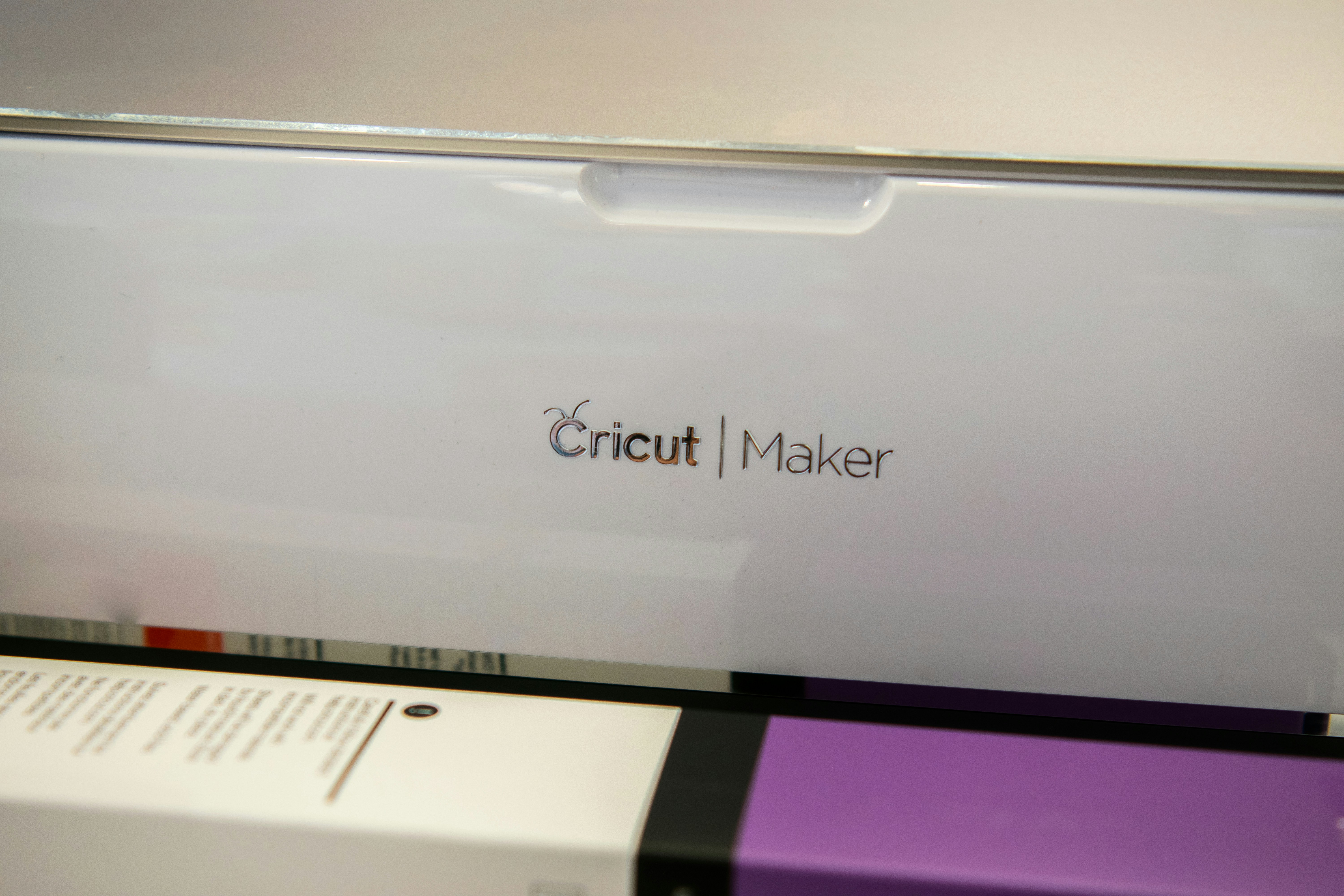 This image showcases a Cricut Maker machine with an array of crafting accessories. Included are various colored vinyl sheets, cutting tools, and pens, all essential for DIY crafting projects. The Cricut Maker is featured prominently, emphasizing its design and functionality in a crafting environment. The accessories are arranged to display the versatility and range of materials compatible with the machine, suitable for scrapbooking, custom designs, and home decor projects.