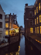 A warm, inviting photo of a local Amsterdam guide smiling beside a canal at sunset.