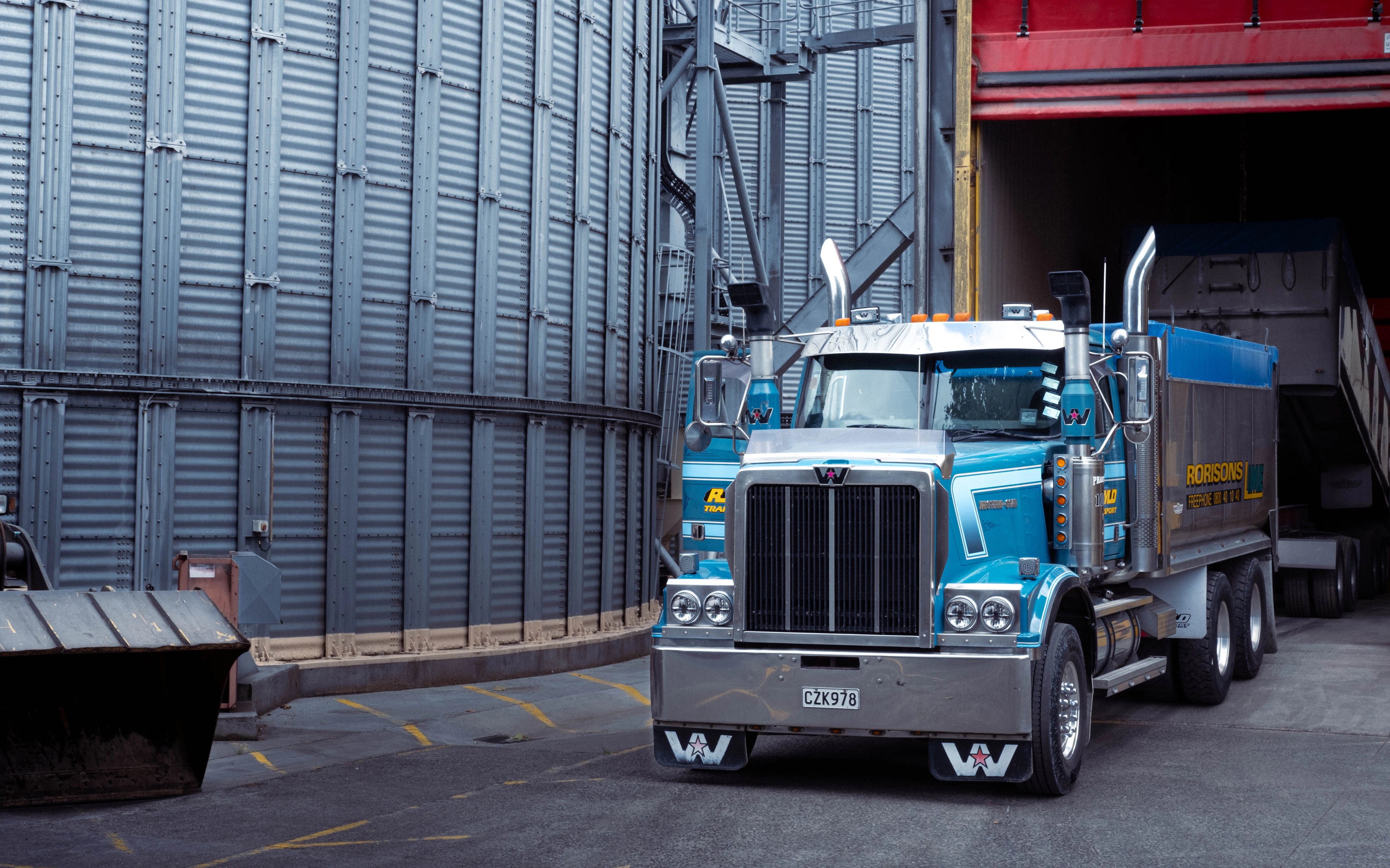 Blue conventional semi-truck parked at an industrial facility
