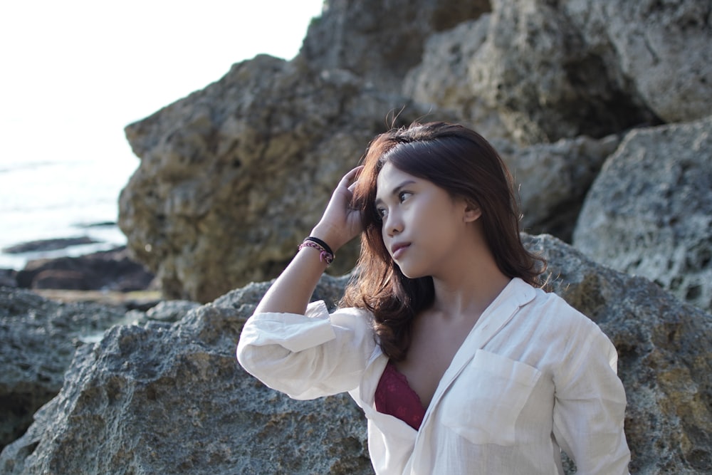 a woman in a white shirt is standing by some rocks
