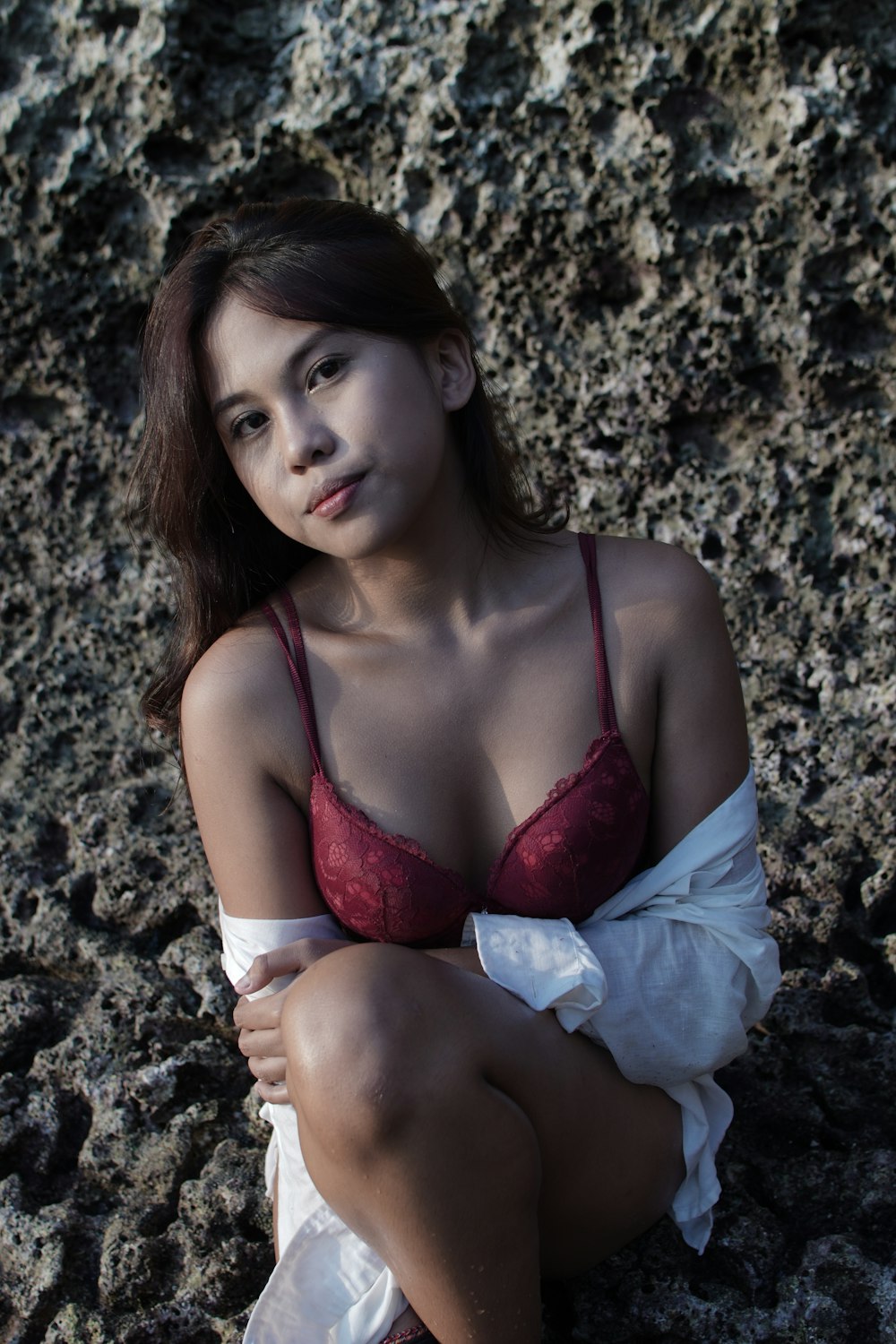 a woman in a red bra top sitting on a rock