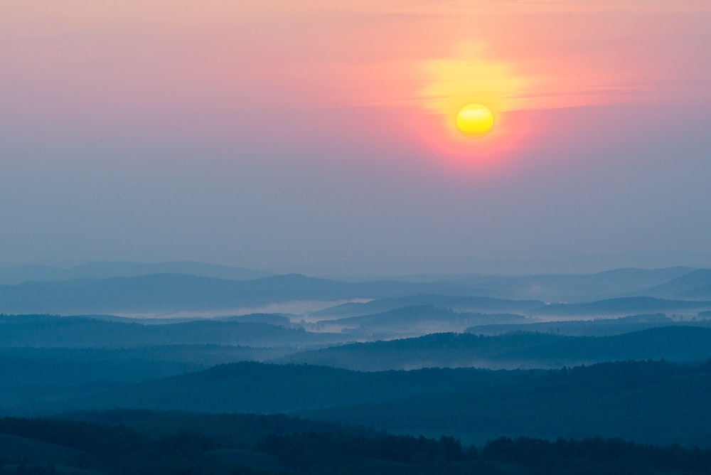 the sun is setting over a mountain range