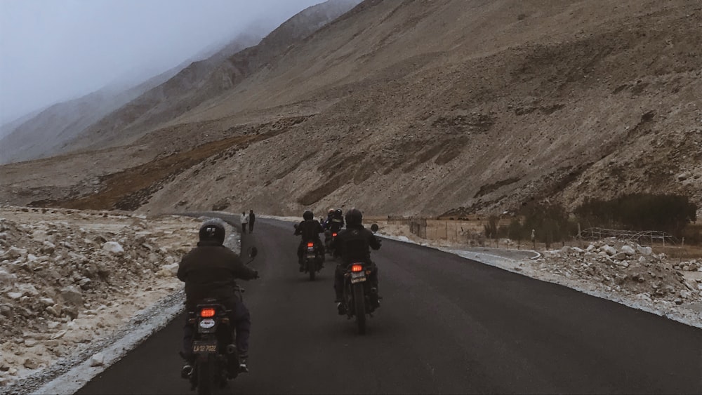 a group of people riding motorcycles down a road