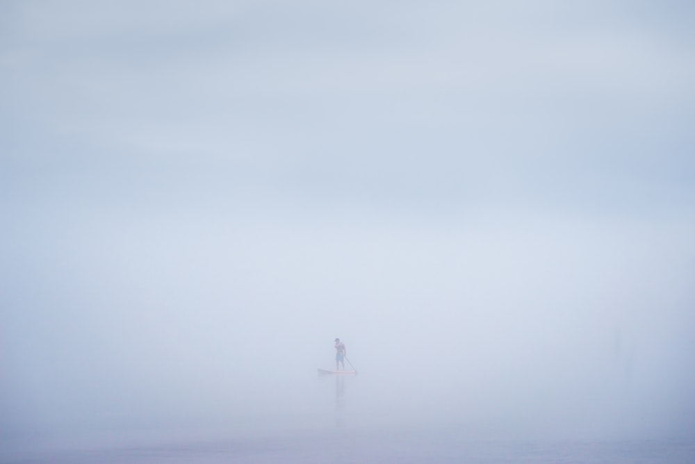una persona de pie sobre una tabla de surf en la niebla