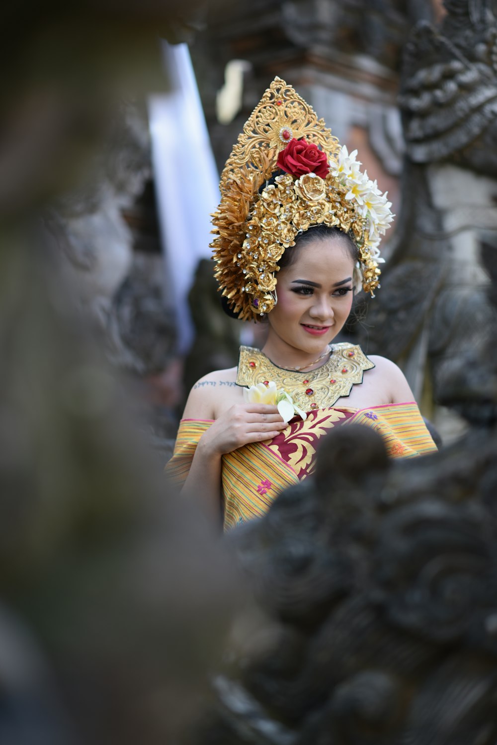 a woman wearing a headdress standing next to a statue