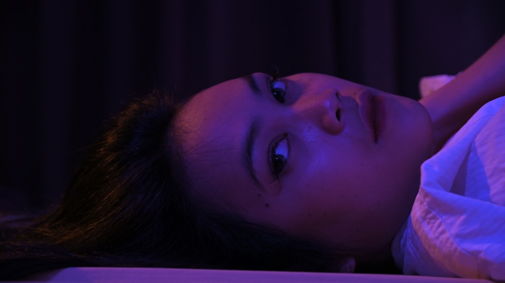 a woman laying on a bed in the dark