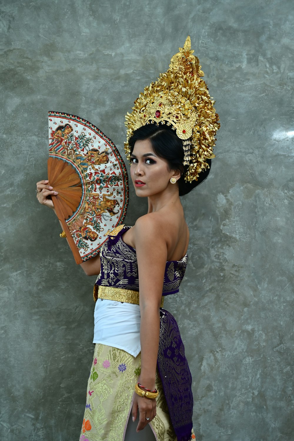 a woman in a thai dress holding a fan