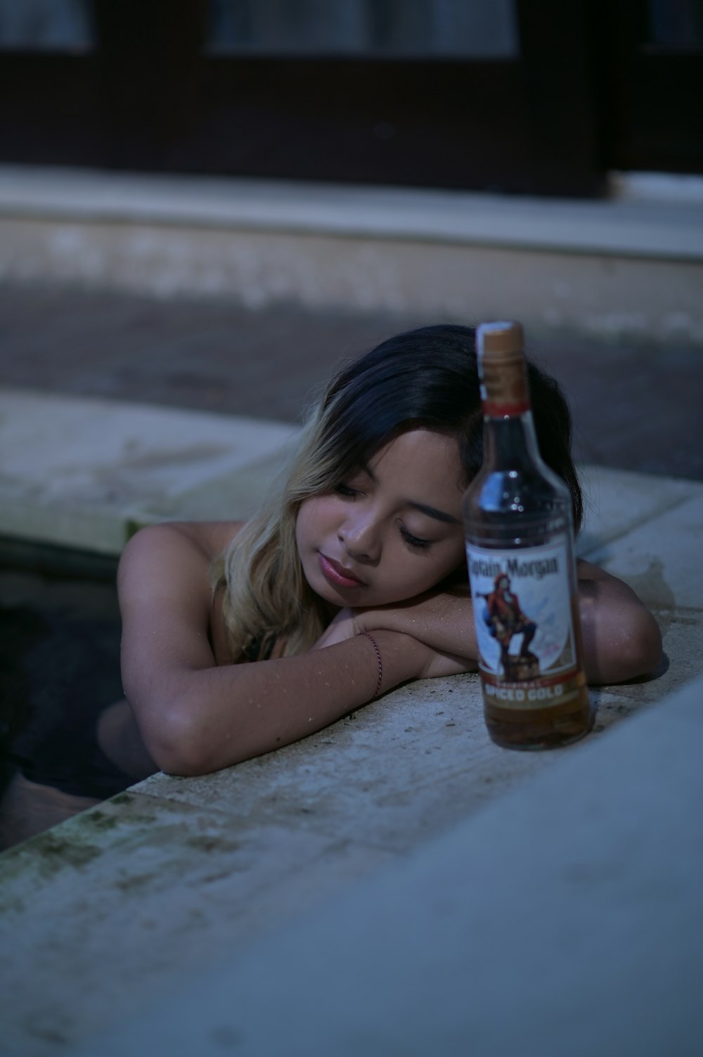 a woman laying on the ground next to a bottle
