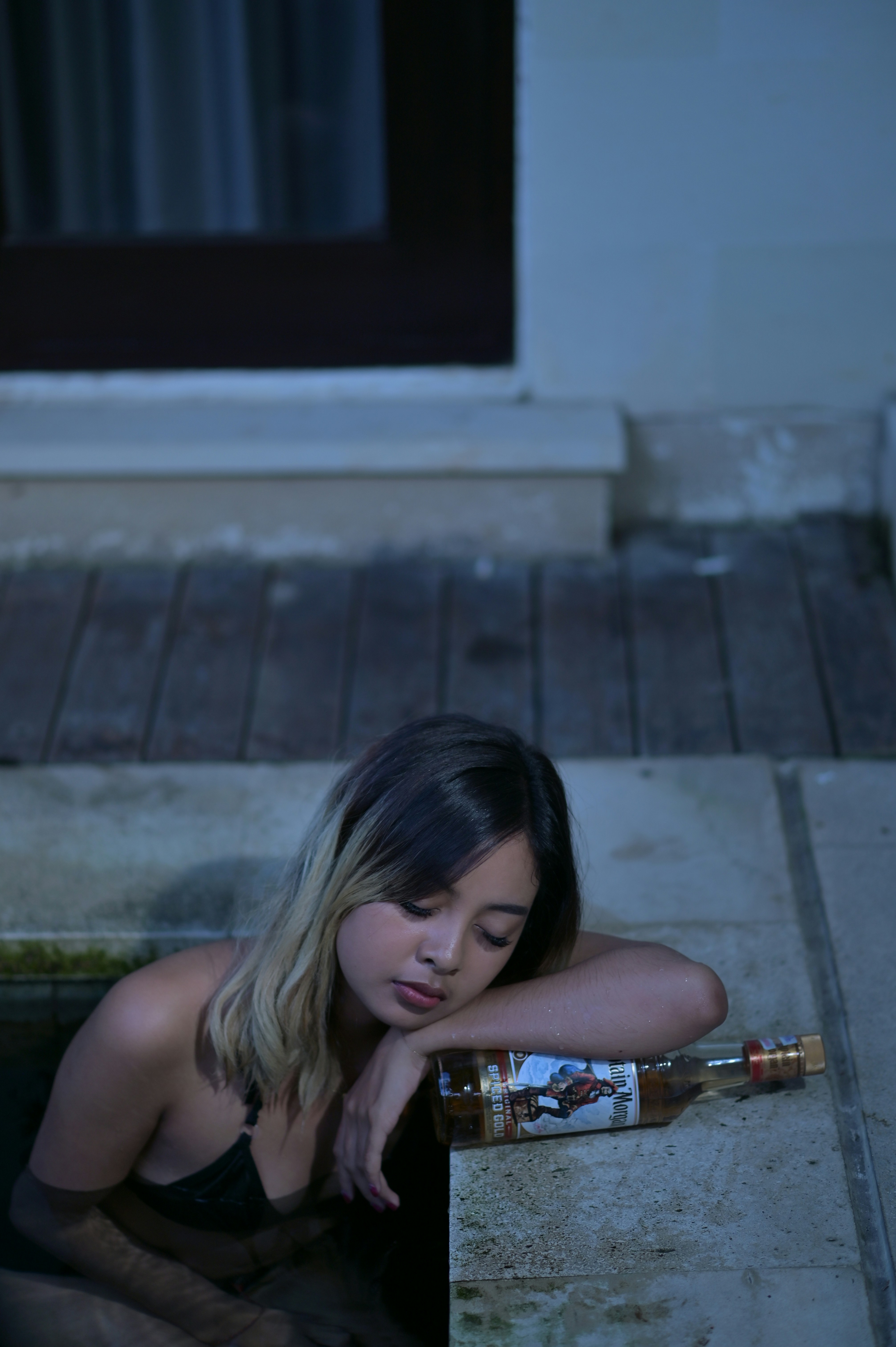 a woman sitting on the ground next to a bottle