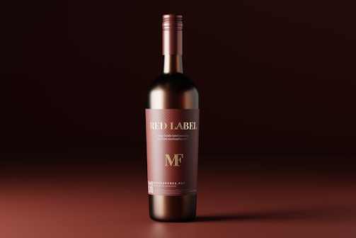 A sophisticated wine bottle with a red label stands upright against a rich, dark brown gradient background. The label features elegant gold lettering with the words 'RED LABEL' and 'MF'. The bottle appears glossy, reflecting light, which enhances its premium appearance.