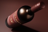 A close-up view of a wine bottle lying on its side. The label on the bottle is prominently displayed, featuring text that includes 'Red Label'. The bottle cap and the label are in shades of red and brown, with a smooth and glossy appearance.