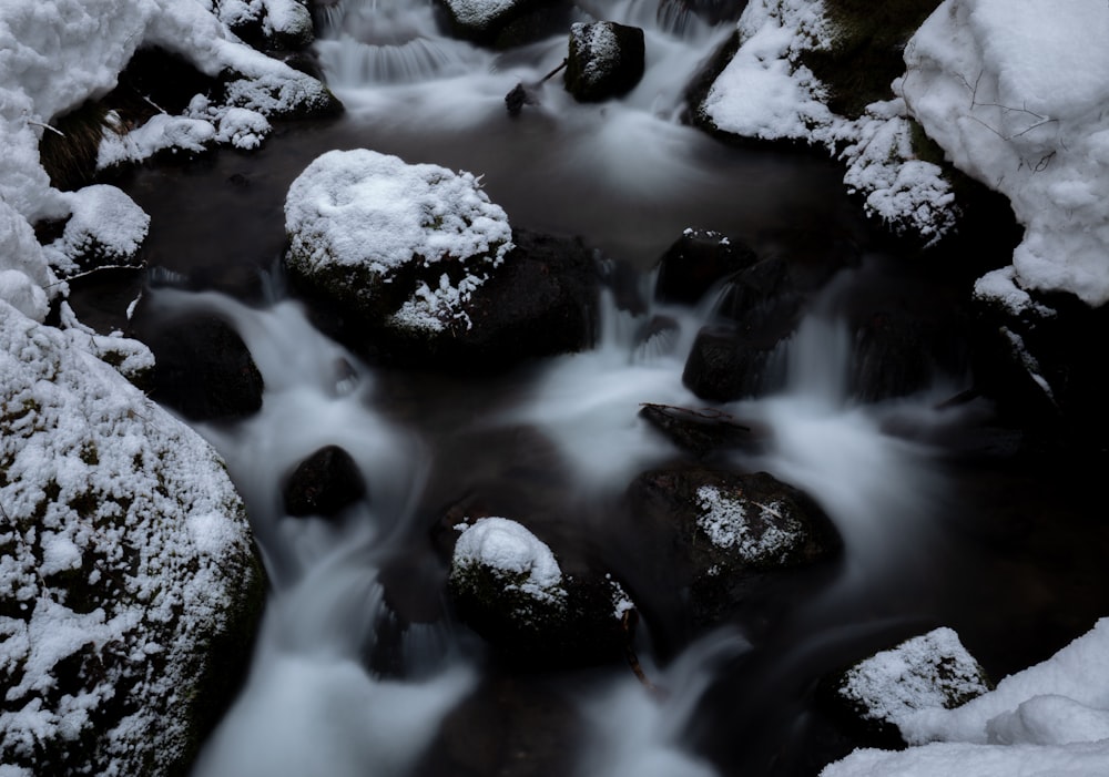 a stream of water surrounded by snow covered rocks