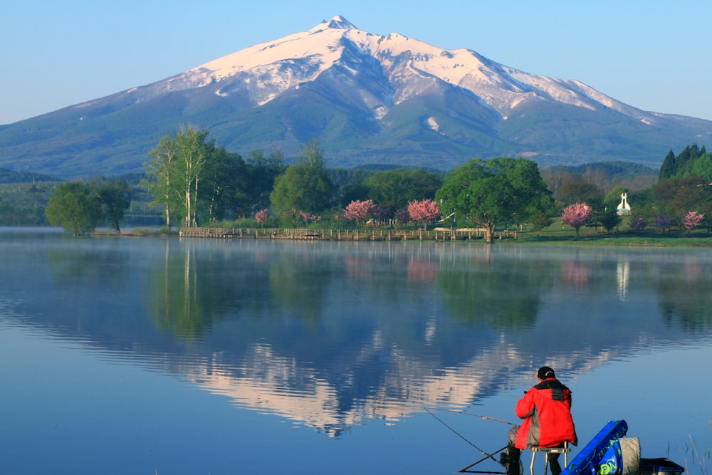 a man fishing on a lake with a mountain in the background