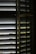A close-up view of wooden window blinds with light filtering through the slats, casting shadows and highlights.