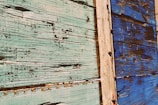 Weathered wooden panels with peeling turquoise and blue paint, featuring visible textures, grains, and rustic charm.