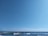 A vast, serene ocean scene under a clear blue sky, with gentle waves rolling towards the shore, creating a calming and peaceful atmosphere.