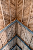 A ceiling made of slanted wooden planks arranged in a chevron pattern, supported by darker wooden beams crossing each other to form triangles.