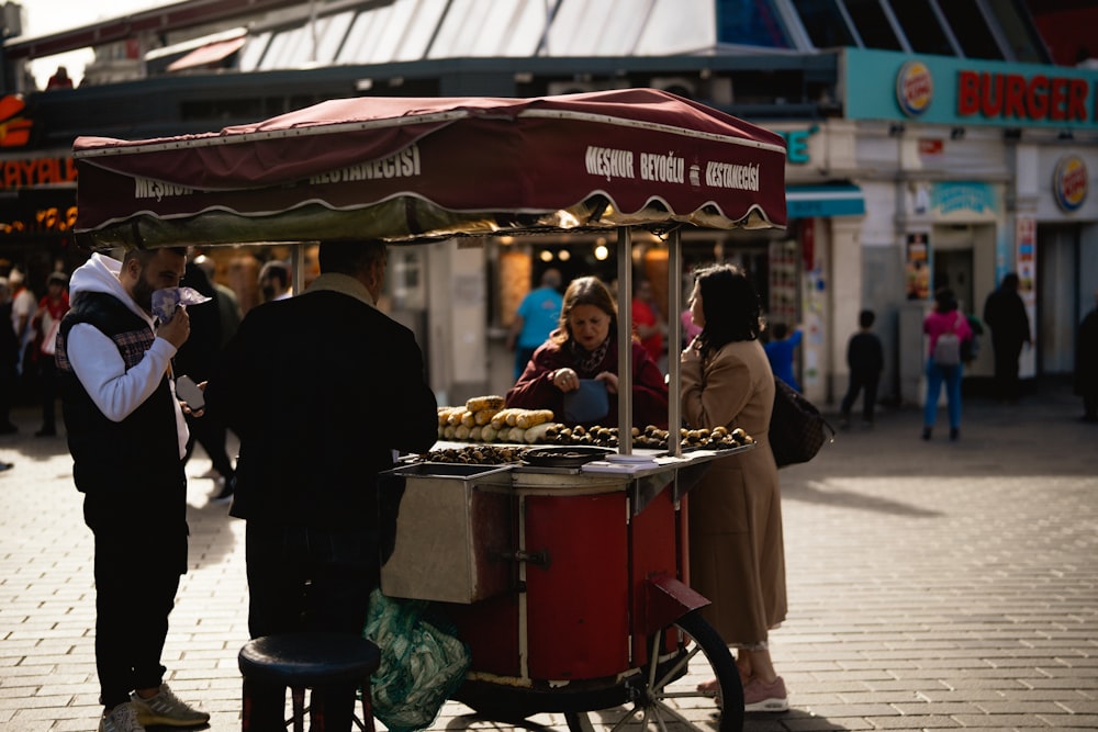 a group of people standing around a food cart