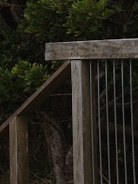 A close-up of a wooden deck railing being carefully examined with a measuring tape.