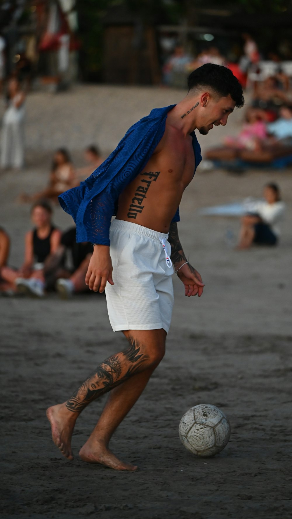 a shirtless man is playing soccer on the beach