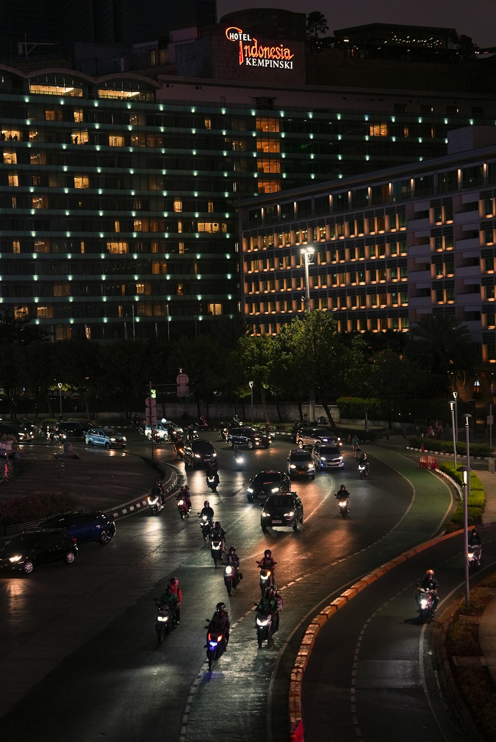 a group of people riding motorcycles down a street at night