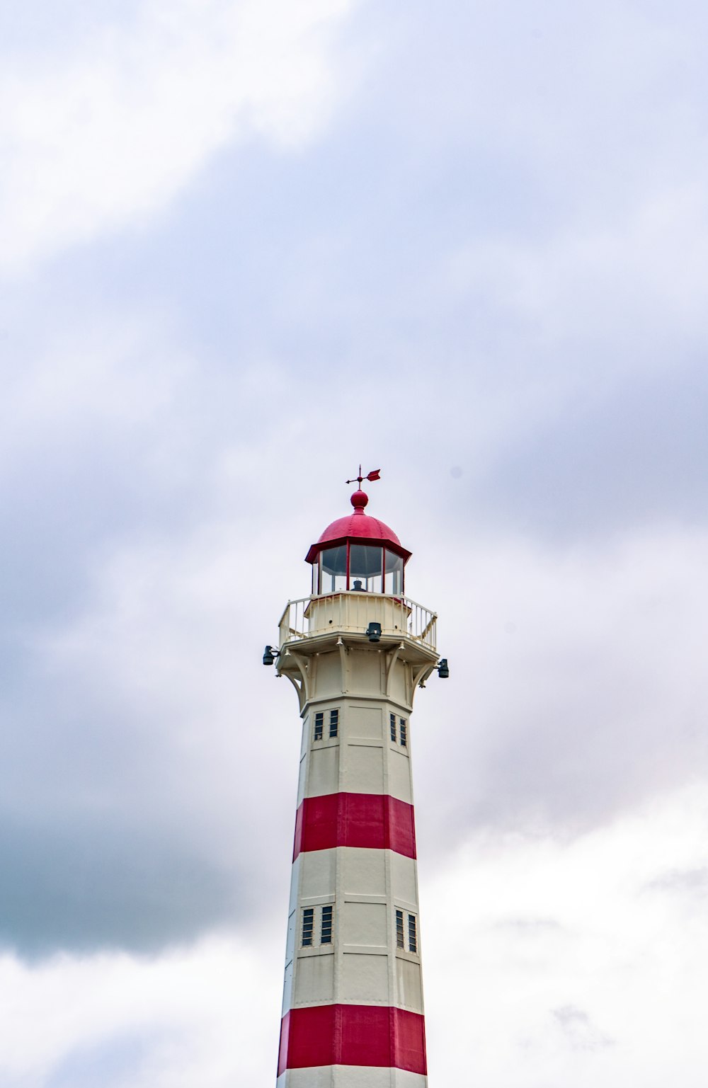 a red and white lighthouse on a cloudy day