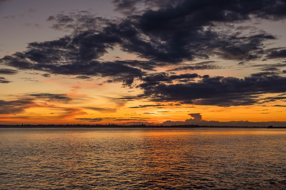 a sunset over a body of water with clouds in the sky